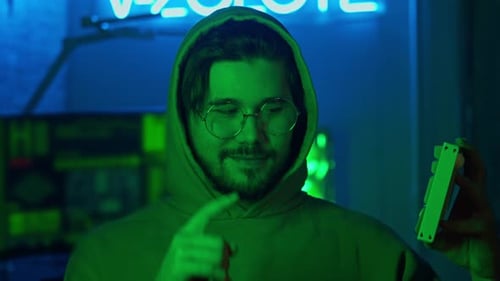 Retrato de um hacker enquanto ele pressiona um botão no teclado e sorri astuciosamente