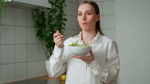Woman Eating Salad in Modern Kitchen
