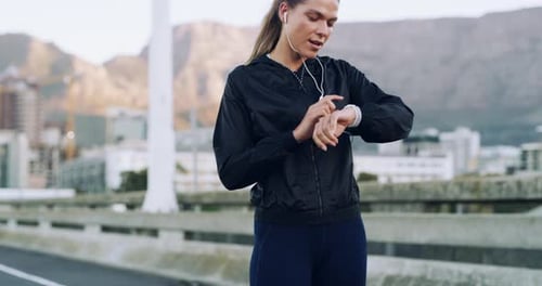 A young woman checking the time during a workout in the city