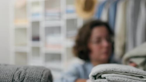 Lifestyle, Female sales assistant Confidently selects clothes from a neatly folded pile Online