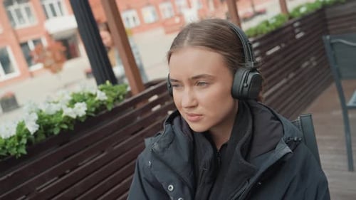 Young Lady on Terrace Questioning Female with Headphones Shows Shifting Emotions Outdoors Close Up
