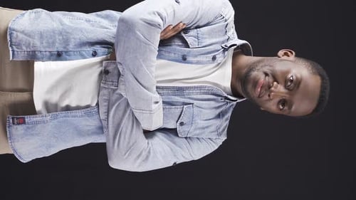 Young Man Smiles with Arms Crossed on Black