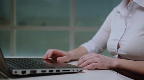 Woman working on laptop computer at desk close-up