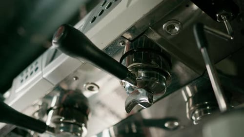 Pouring coffee flows from the machine into the cup making hot drink using the filter holder freshly