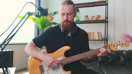 Young Famous Caucasian Man Plays Guitar and Performs Songs Sits in Home Studio