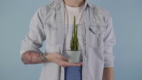 Close Up of Man Holding Houseplant in His Hand with Studio Background