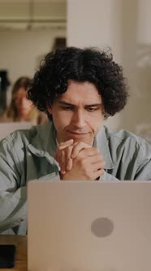 Focused Young Man Working on Laptop in Bright Modern Coworking Space with Casual Atmosphere Natural