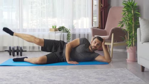 Man Exercising Leg on Yoga Mat in Home