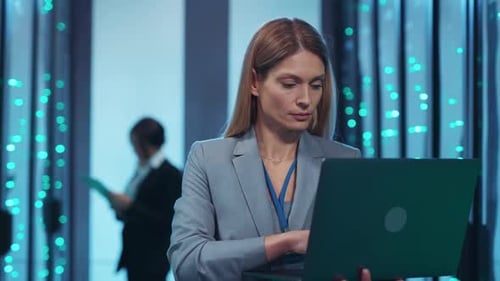 A Woman Uses a Laptop in a Modern Data Center Showcasing Tech