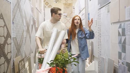 Man Pushes a Shopping Cart Woman Walks with Surprise in the Tile Department in Construction Store