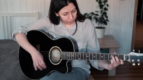 Woman Plays Acoustic Guitar at Home