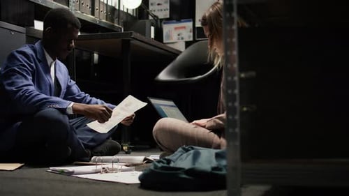 Colleagues Collaborate on Floor in Dark Office