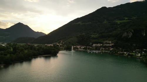 bird view of great mountains hiding a small town under the hills by the water with a great fountain