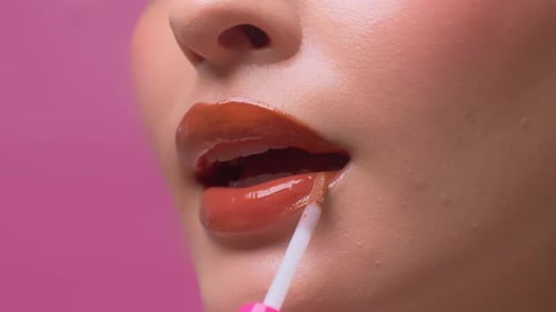Gros plan d'une femme appliquant du brillant à lèvres sur ses lèvres rouges sexy. Sensuel aux lèvres charnues.