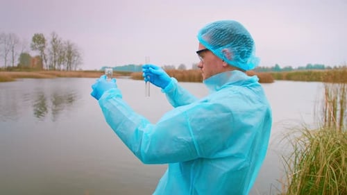 Scientist Tests Water by Lake with Test Tubes