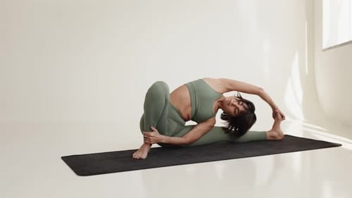 Woman Performing Advanced Yoga Pose in Sunlit Studio Setting