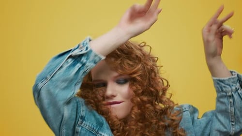 Closeup Joyful Woman Dancing in Studio. Playful Girl Jumping on Yellow Background