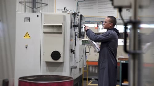 Millennial machinist skillfully operating equipment in machine shop factory floor