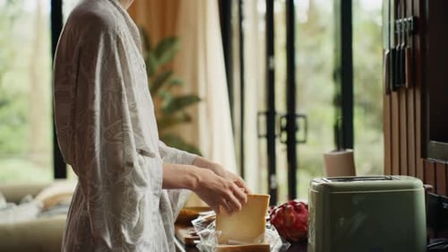Woman in Robe Prepares Toast in Modern Kitchen