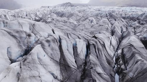 Aerial Pan Over Iceland Glacier with Ash Streaks and Crevasses