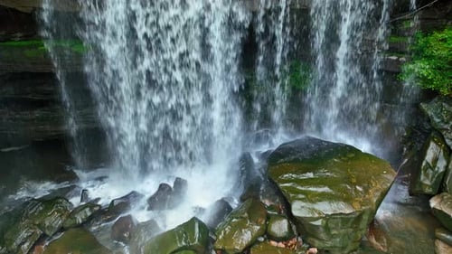 A stunning waterfall cascading gracefully amidst vibrant greenery. Aerial view.