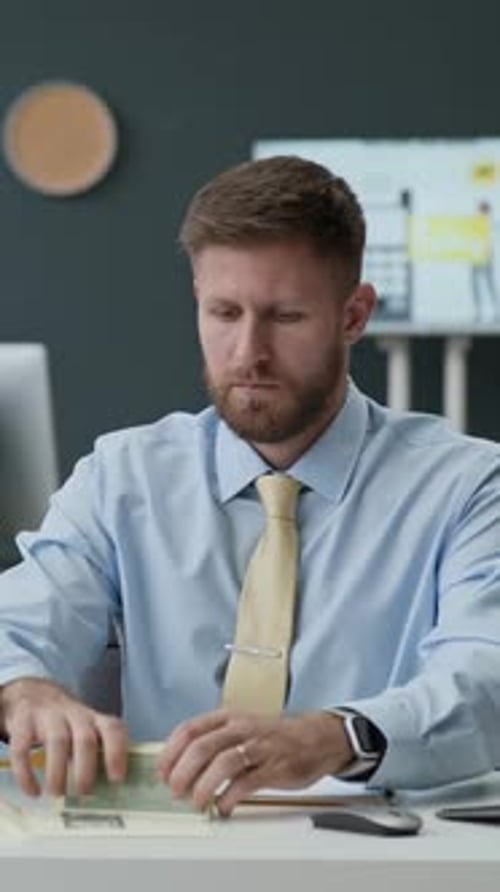 Employee Counting Banknotes while Colleague Using Tablet Talking in Bank Office