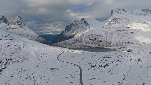 Snowy mountain road winds through winter landscape in Norway