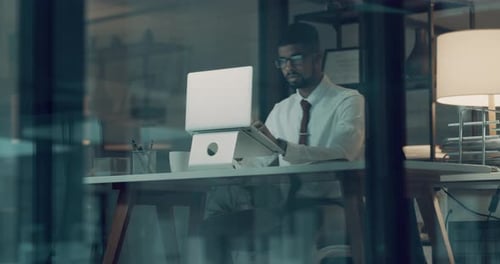 4K-Videomaterial eines jungen Geschäftsmannes, der in einer späten Nacht bei der Arbeit einen Laptop benutzt
