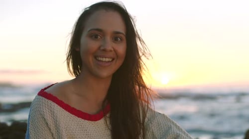 Portrait of a happy young woman enjoying a relaxing sunset view by the sea