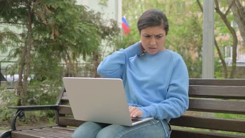 Woman Works on Laptop, Relaxes on Park Bench
