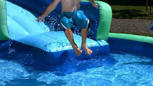 Boy Jumping into Water from Inflatable Slide
