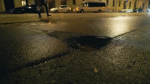 Kanaldeckel auf Asphaltstraße bei Nacht neben einem Gebäude