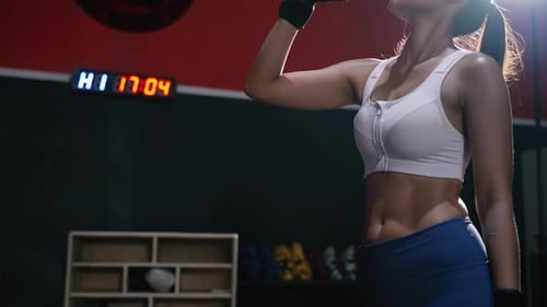 Fit Woman Drinking Water in Gym After Workout