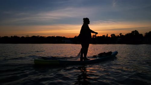 Woman Paddleboarding on Lake at Sunset