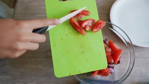 Frisches Gemüse für einen Salat auf einem grünen Schneidebrett auf einem Holztisch hacken