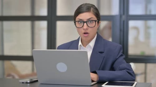 Businesswoman Expressing Worry While Using Laptop in Office