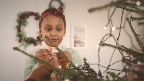 Child Decorating Christmas Tree with Lights and Ornaments