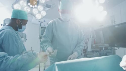 Gliding Shot of Diverse Team of Professional Surgeons Performing Invasive Surgery on a Patient in t
