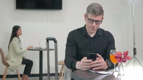 beautiful businessman with luggage sitting on lounge play smartphone while waiting for boarding