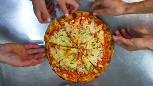 Hands Taking Pizza Slices From a Round Board