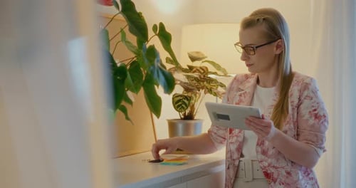 Woman Uses Tablet, Writes Note Indoors