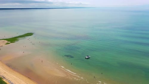 Sweeping Aerial of Stranded Boat on Tidal Flats with Tide Pools and Marsh Grass