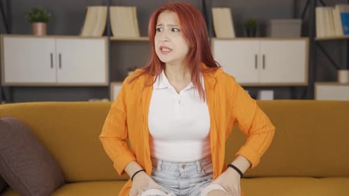 Distressed Young Woman Expressing Sadness on Couch