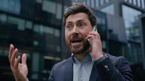 Irritated Businessman Talking on Phone in City