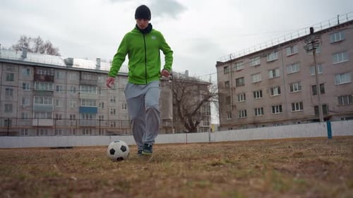 Man Wearing Bright Hoodie Dribbles Across Field with Focus Athlete in Luminous Green Sweatshirt