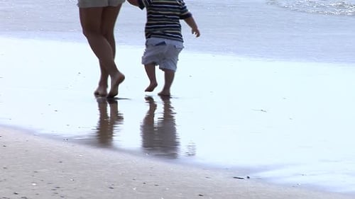 Happy mother and son playing together on a sunny beach vacation in summer