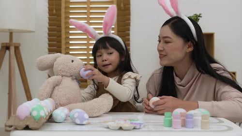 Child and Woman Decorating Easter Eggs with Bunny Ears