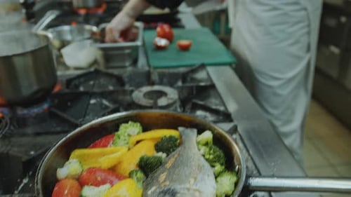 Chef Cutting Tomatoes and Talking with Coworker in Restaurant Kitchen
