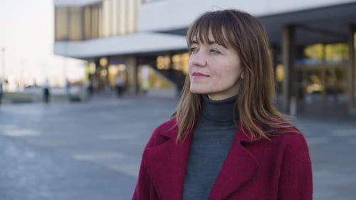 An Attractive Middleaged Caucasian Woman Looks Around with a Melancholic Smile in an Urban Area