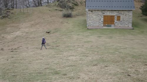 Caucasian Mature Woman with a Hat Dressed in Comfortable Clothes and a Backpack Crosses the Mountain